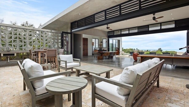 An outdoor patio with wooden furniture, a dining area, and a view of the ocean.