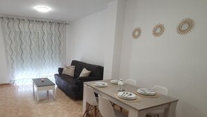 Un coin repas avec une table dressée pour quatre personnes, un canapé et une fenêtre avec des rideaux.