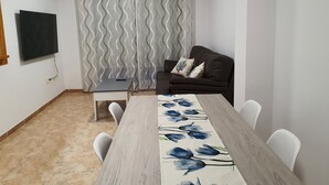 Un salon avec un canapé marron foncé, une table basse en bois et un téléviseur fixé au mur.
