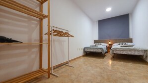 Une chambre avec deux lits simples, une armoire en bois et un portant à vêtements.