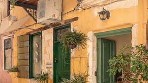 Un edificio amarillo con una puerta verde, un balcón con plantas y un letrero que dice 'ANTICA CASA STUDIOS'.