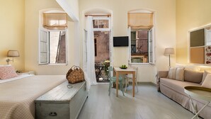 Una habitación acogedora con cama, sofá, mesa de comedor con sillas y televisión instalada en la pared.