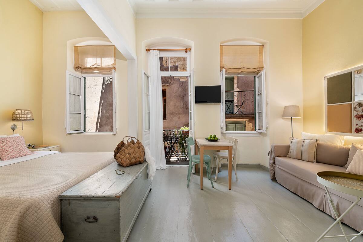 Une pièce confortable avec un lit, un canapé, une table à manger avec des chaises et un téléviseur fixé au mur.
