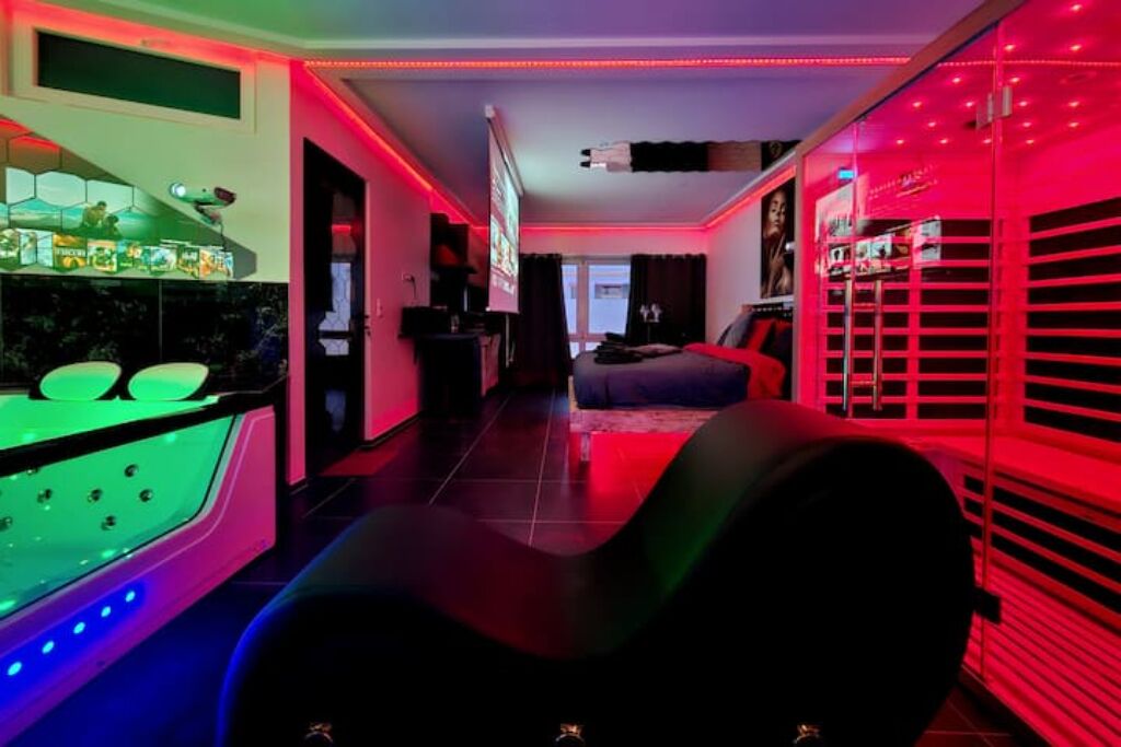 A room with a curved black chair, a green illuminated bar, and red ambient lighting.