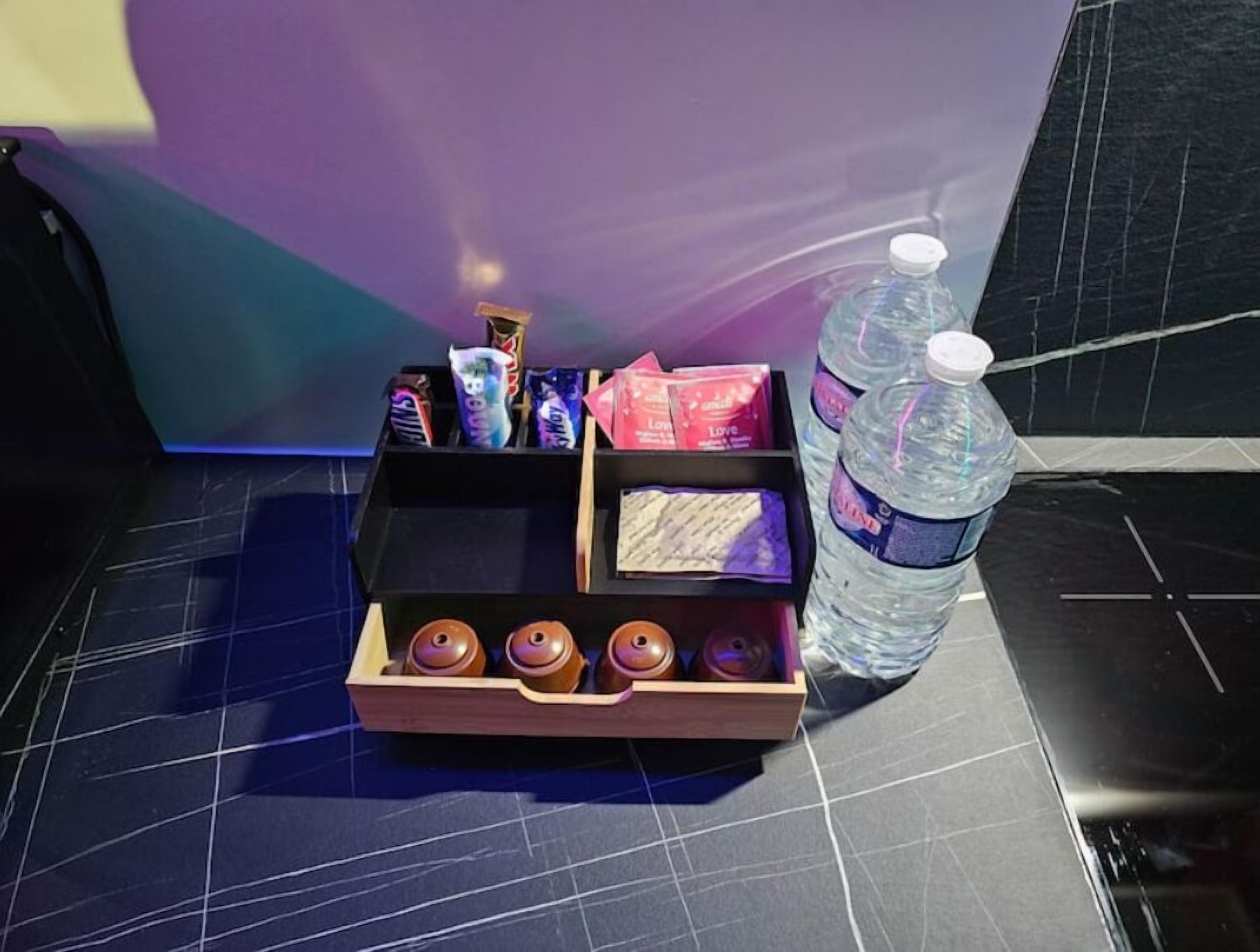 Un vassoio con snack, una bottiglia d'acqua e una scatola di cioccolatini su un tavolo.