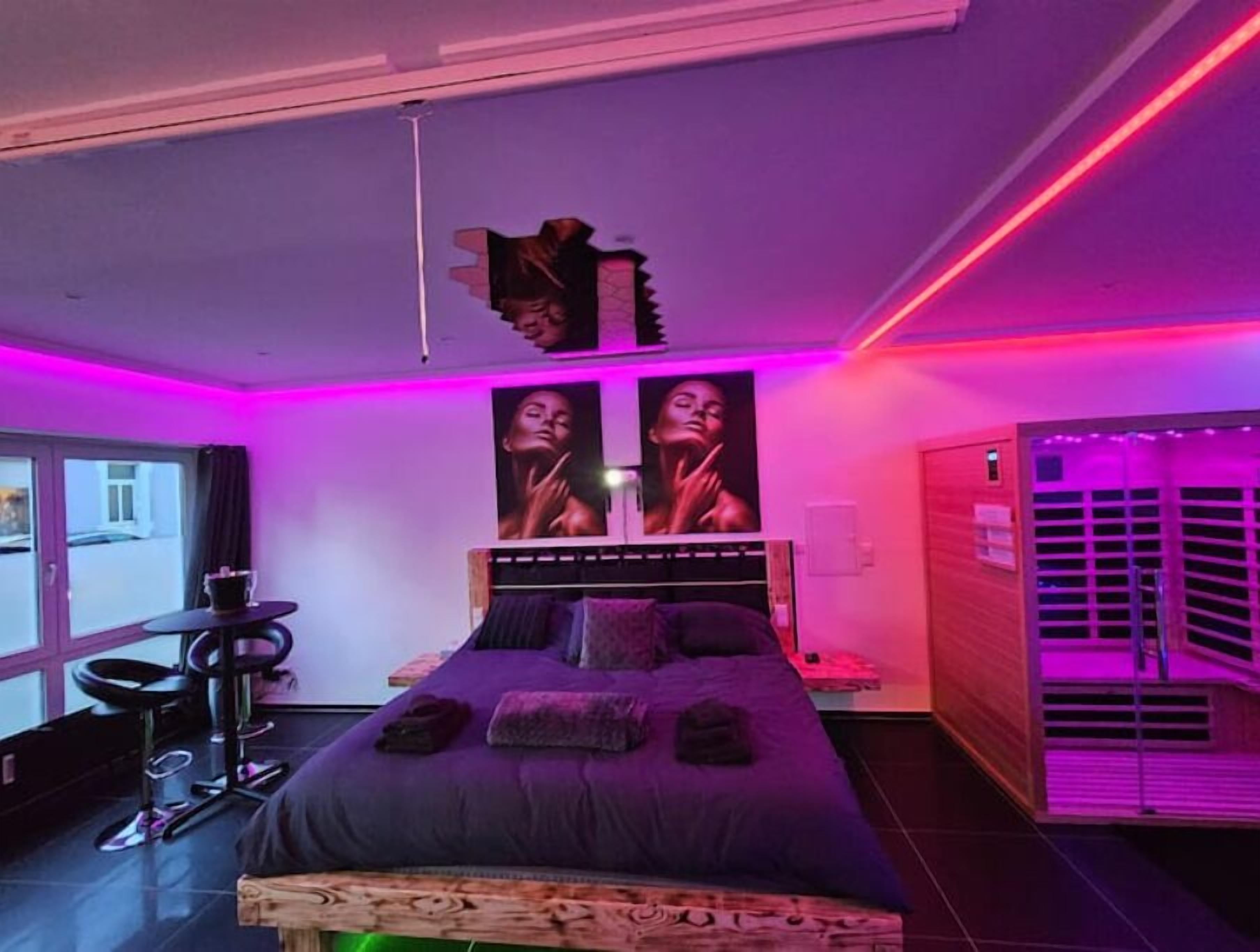 Ein modernes Schlafzimmer mit Bett, einer Bank, einem Schreibtisch und einem Fenster.