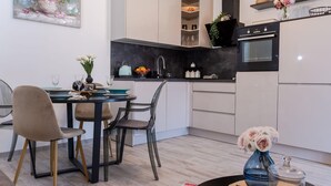 Una cocina moderna con comedor, que presenta una mesa redonda, sillas y un florero con flores.