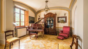 Una sala espaiosa amb un gran piano, un sofà vermell i un moble de fusta amb portes de vidre.