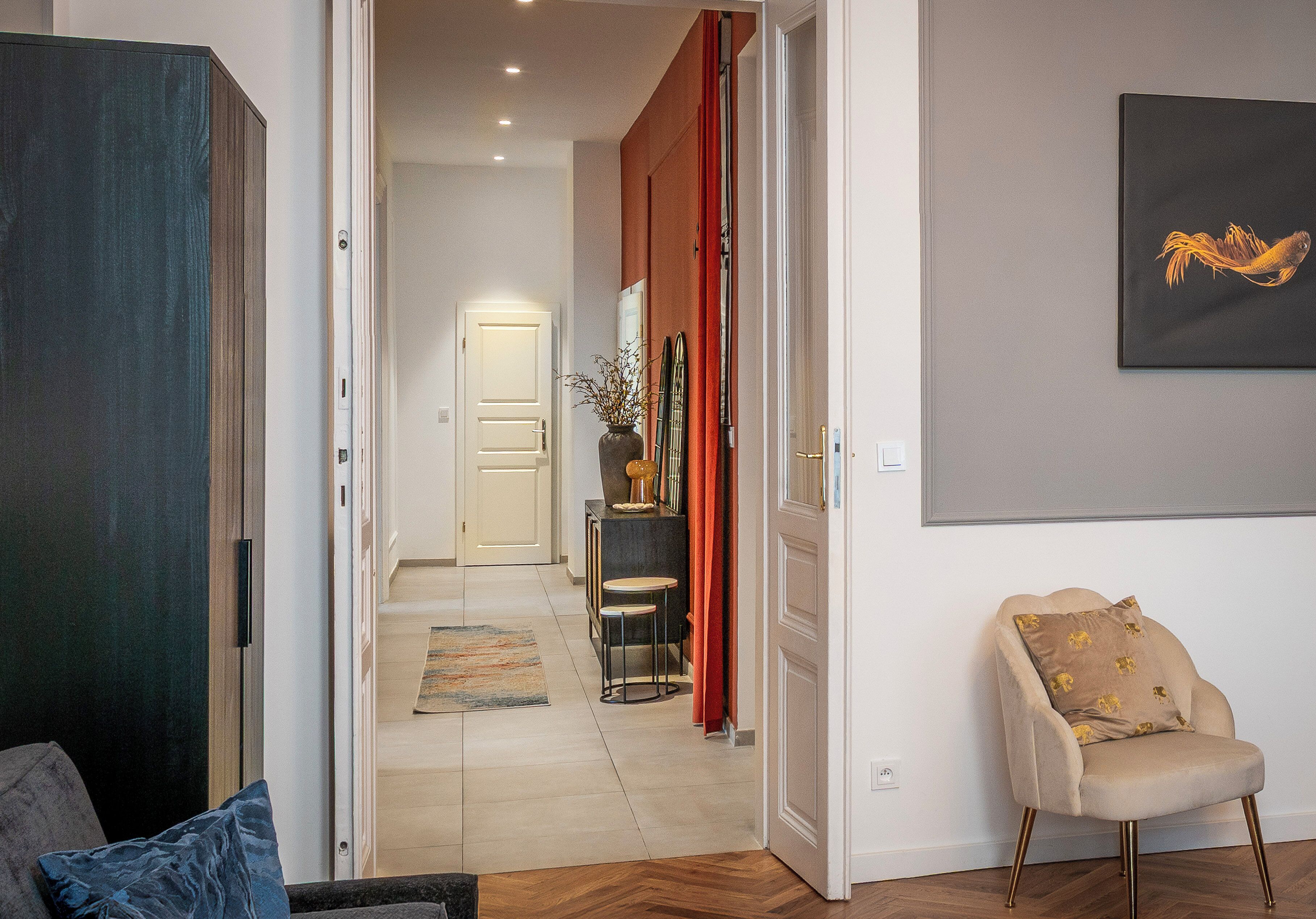 A hallway with a chair, a door, and a painting on the wall.