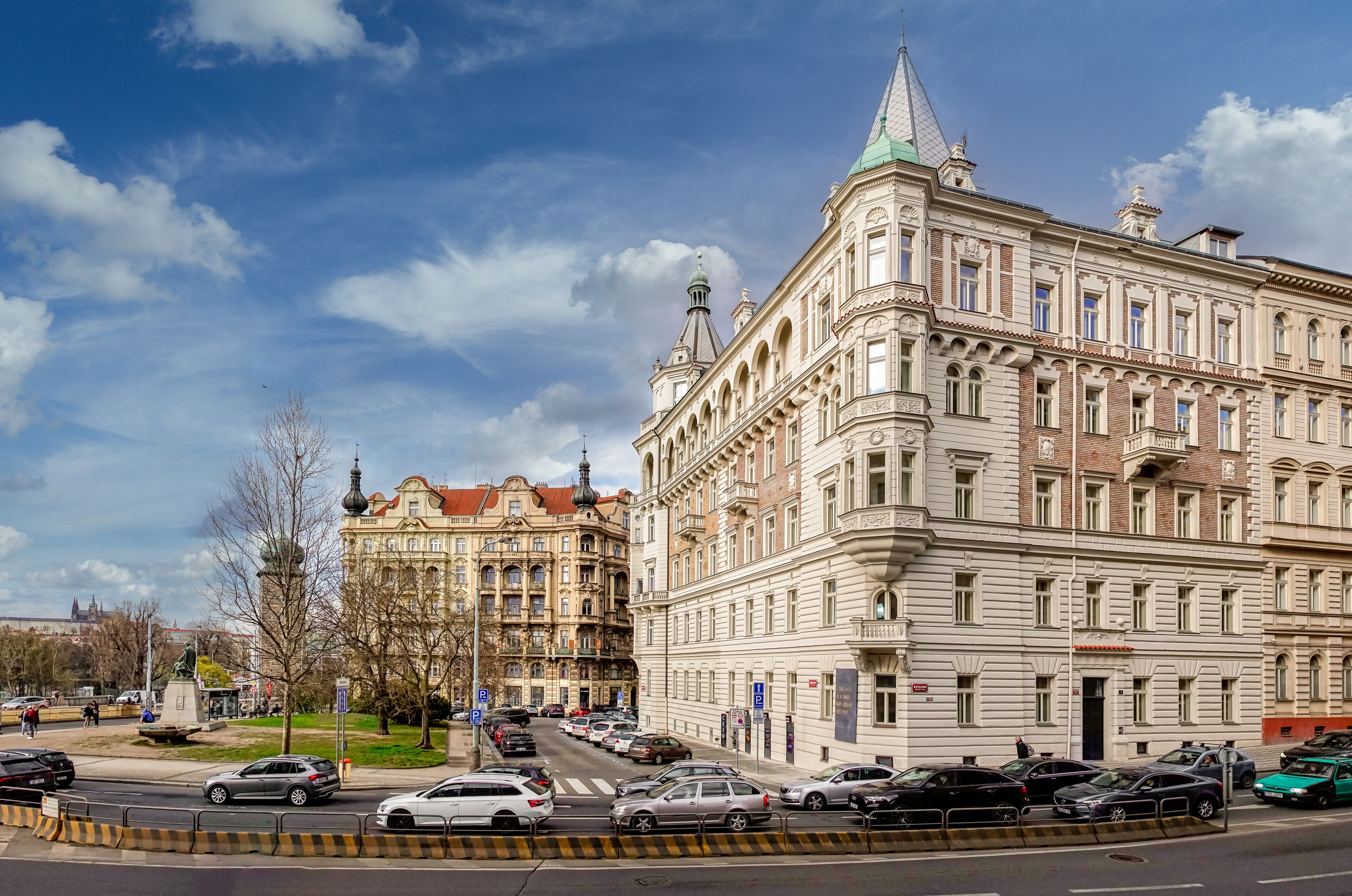 A historic building with classical architecture, a street with parked cars, and a clear sky.