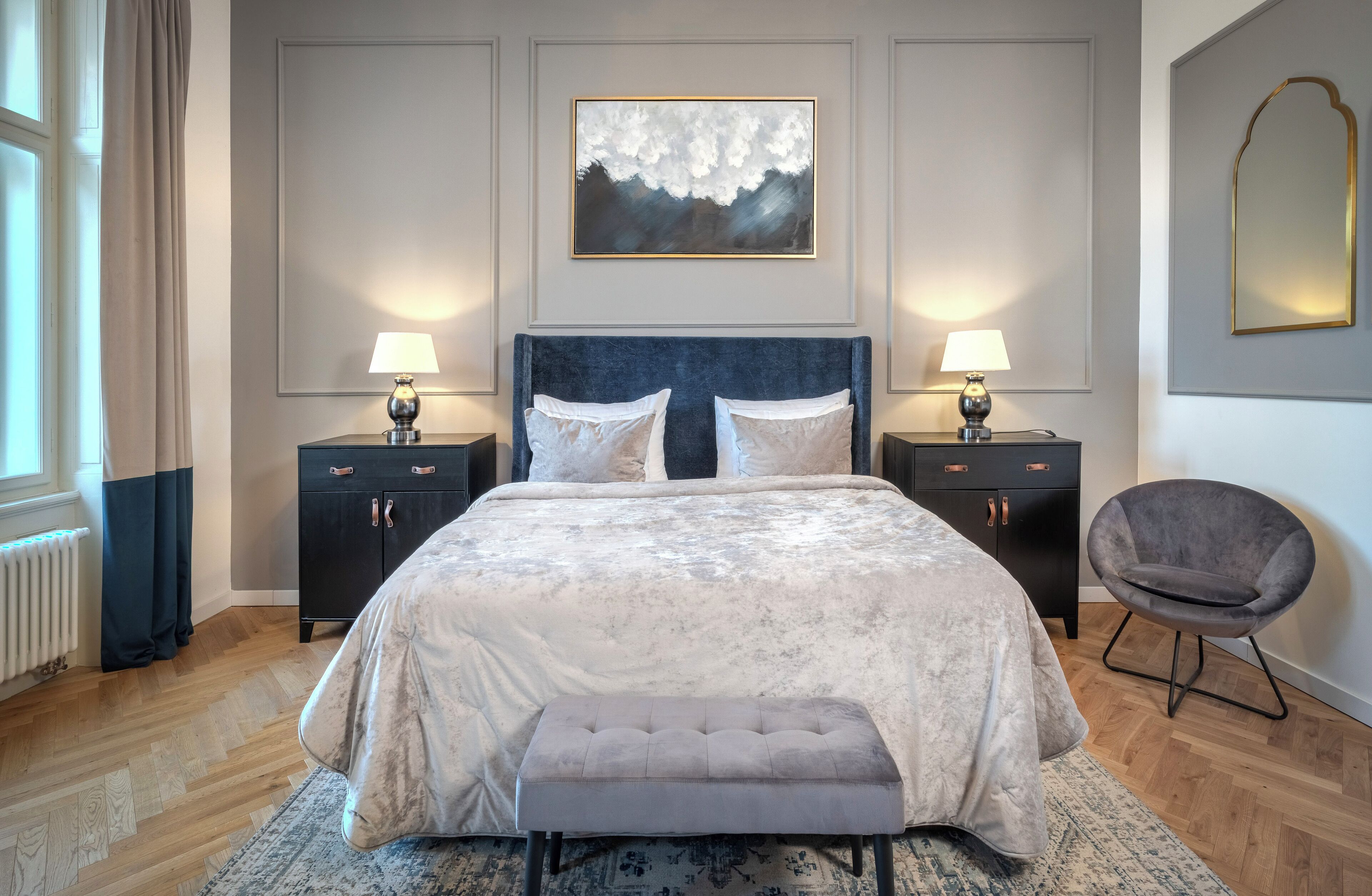Een slaapkamer met een groot bed, twee nachtkastjes met lampen, een stoel en een schilderij aan de muur.