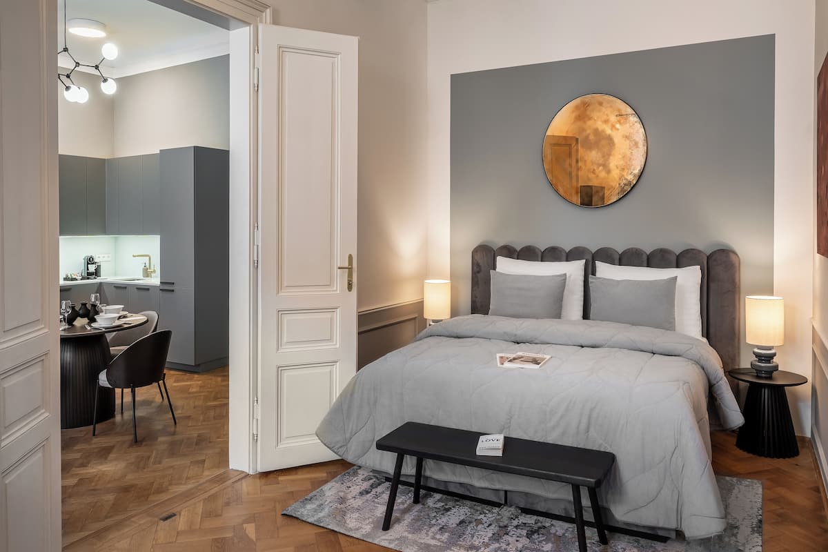 A bedroom with a bed, bedside tables, a desk, and a chair.