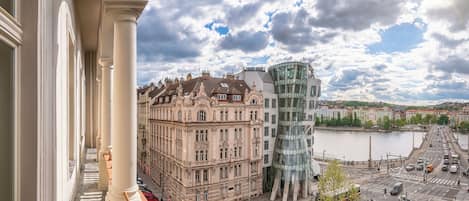 A view of a historic building with a modern glass structure across a river.