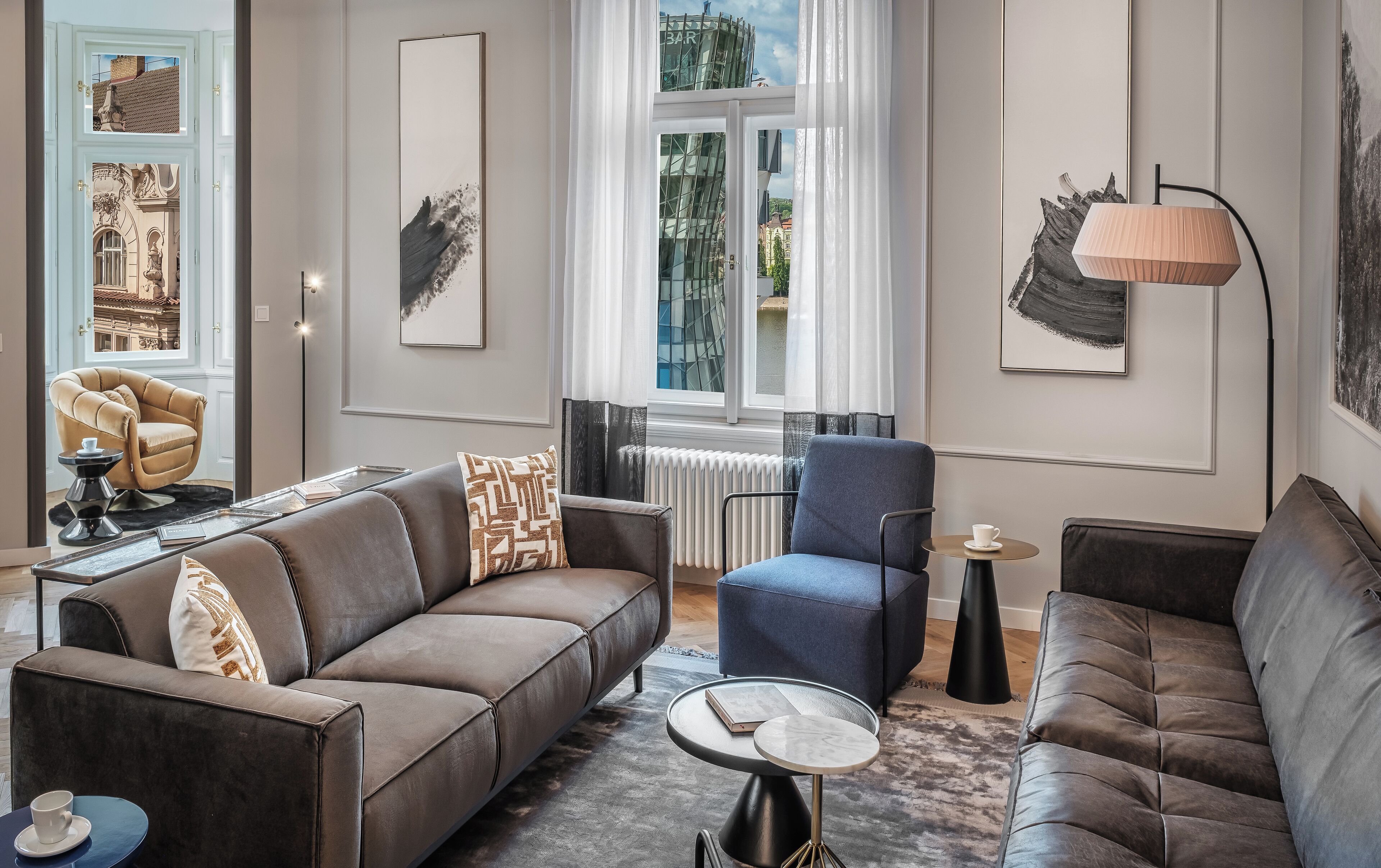 A modern living room with a brown sofa, a blue armchair, and a small round table with a book and a cup.