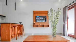 Eine moderne Küche mit einer Holz-Kochinsel, Barhocker, einem flachbildschirmfernseher an der Wand und einer Vase mit Blumen auf einem Tisch.