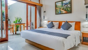Ein Hotelzimmer mit einem großen Bett, einem Bild an der Wand und Blick ins Freie.