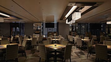 Un restaurante moderno con un patrón geométrico en el suelo, sillas a rayas e iluminación contemporánea.