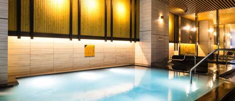 Una piscina interior moderna con un panel de madera y suelo de baldosas.