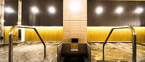 A hot spring bath area with wooden paneling and metal railings.