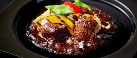 A dish with grilled vegetables and meat on a black plate.