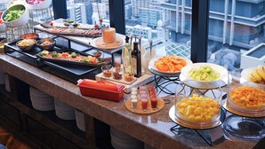 Un bufé con diferentes alimentos y salsas, con vista a un paisaje urbano.