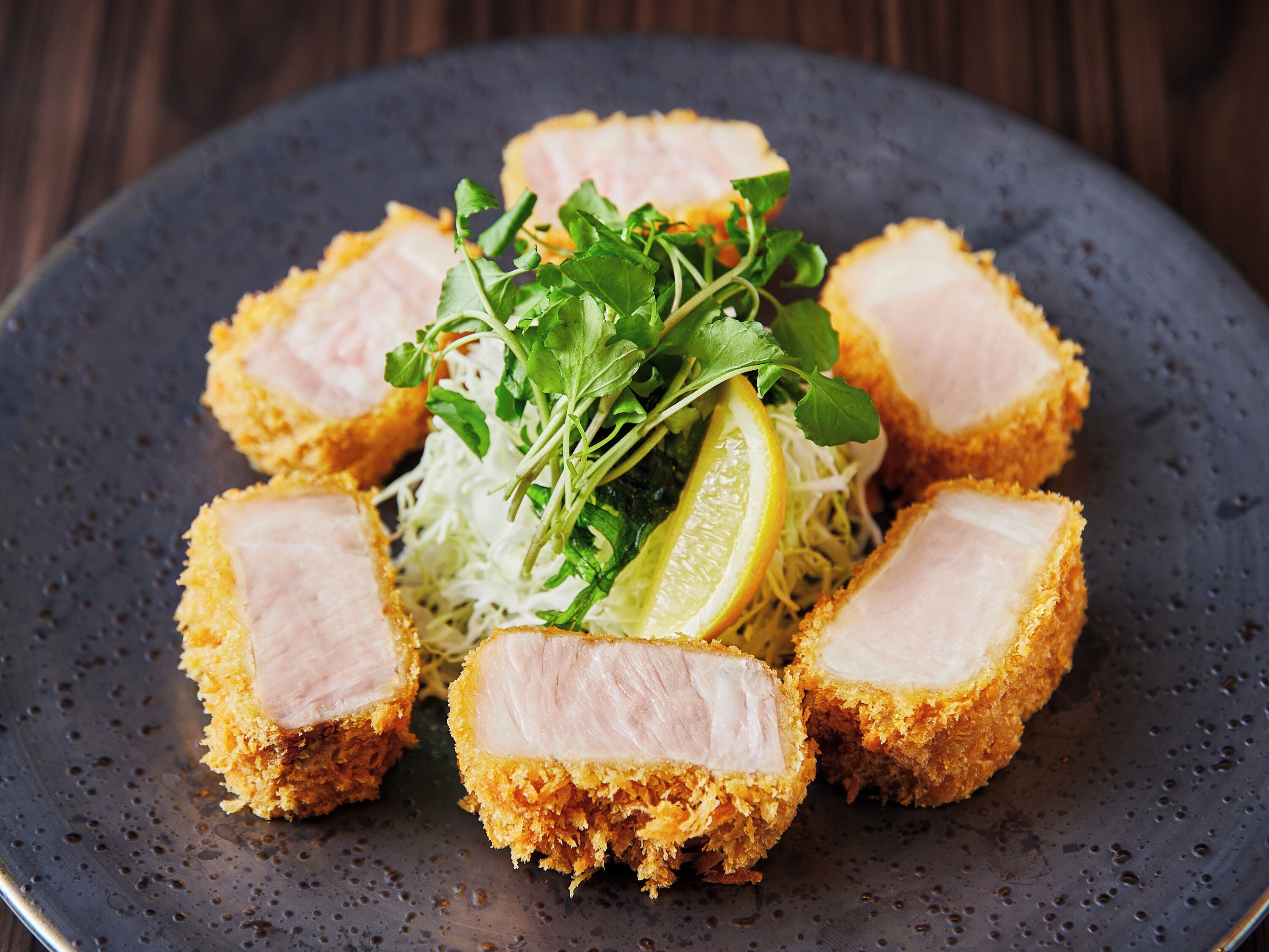 A plate of crispy pork belly with garnishes.