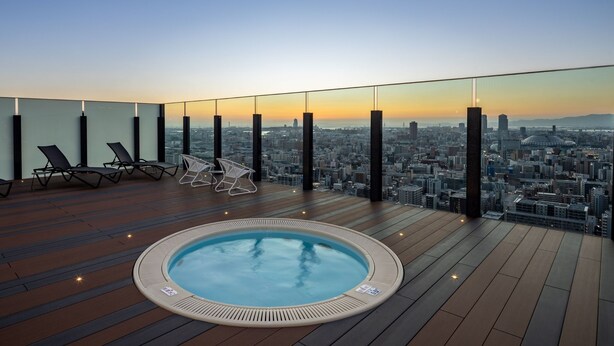 Terraza en la azotea con jacuzzi, sillones de descanso y vistas a la ciudad.