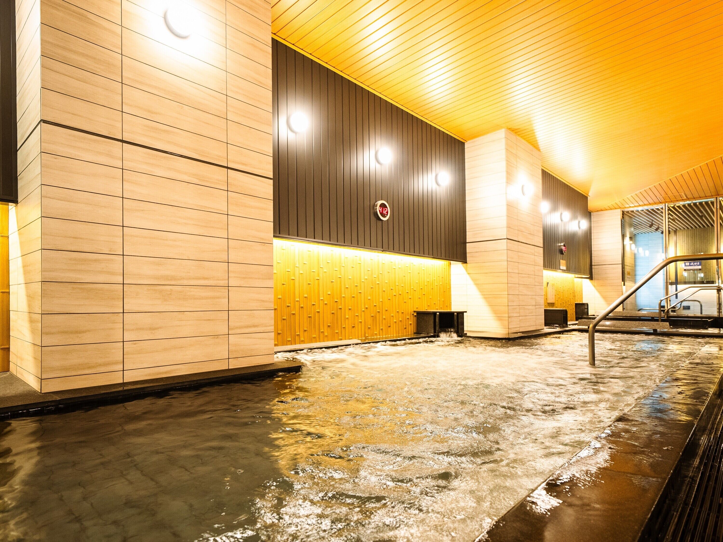 A modern indoor pool area with wooden paneling and a central water feature.