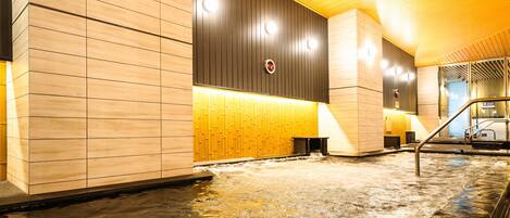A modern indoor pool area with wooden paneling and a central water feature.