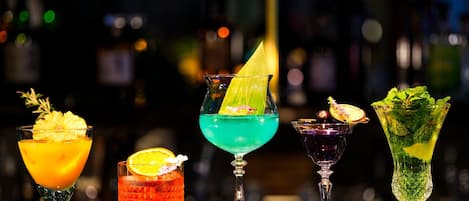 Four cocktails on a bar counter with a blurred background of bottles.