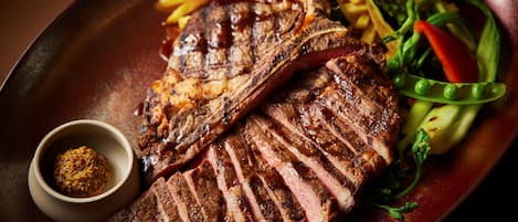 A plate with sliced steak, fries, and a side salad.