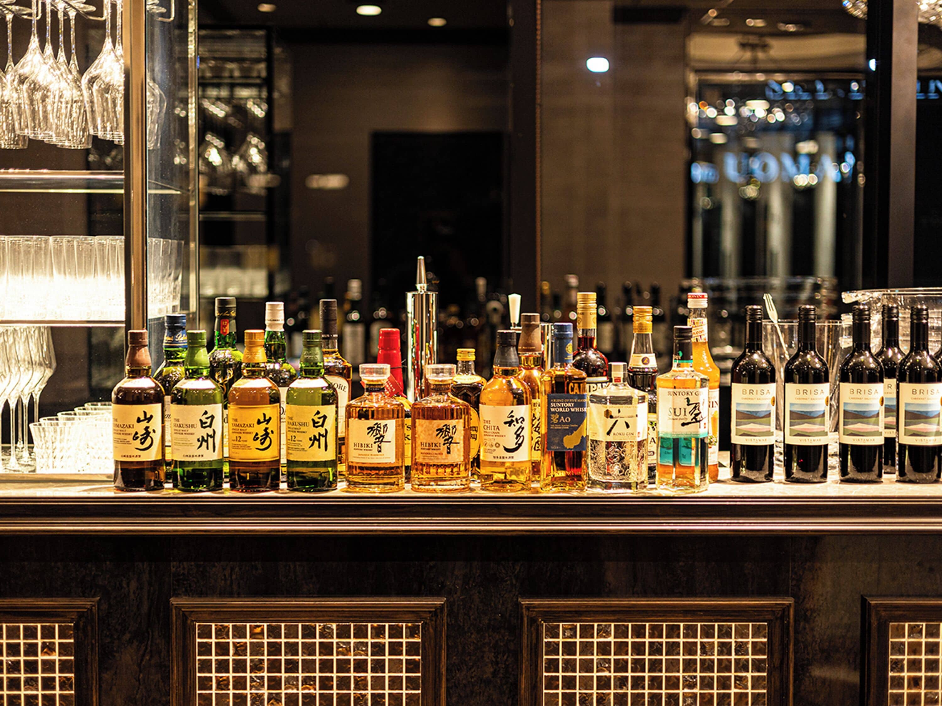 A bar counter with various bottles of alcohol and glasses.