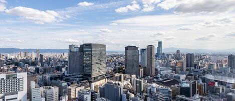 A cityscape with various buildings, including high-rise structures and smaller buildings, under a partly cloudy sky.