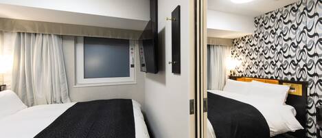 A hotel room with two beds, a TV, a window with curtains, a patterned wall, and a carpeted floor.