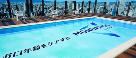 Kattouima-allas, josta avautuu näkymä kaupunkiin, japaninkielistä tekstiä ja modernit tuolit.