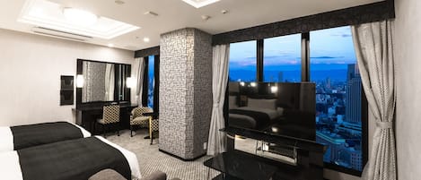 A modern hotel room with a large bed, a sofa, a TV, and a city view.
