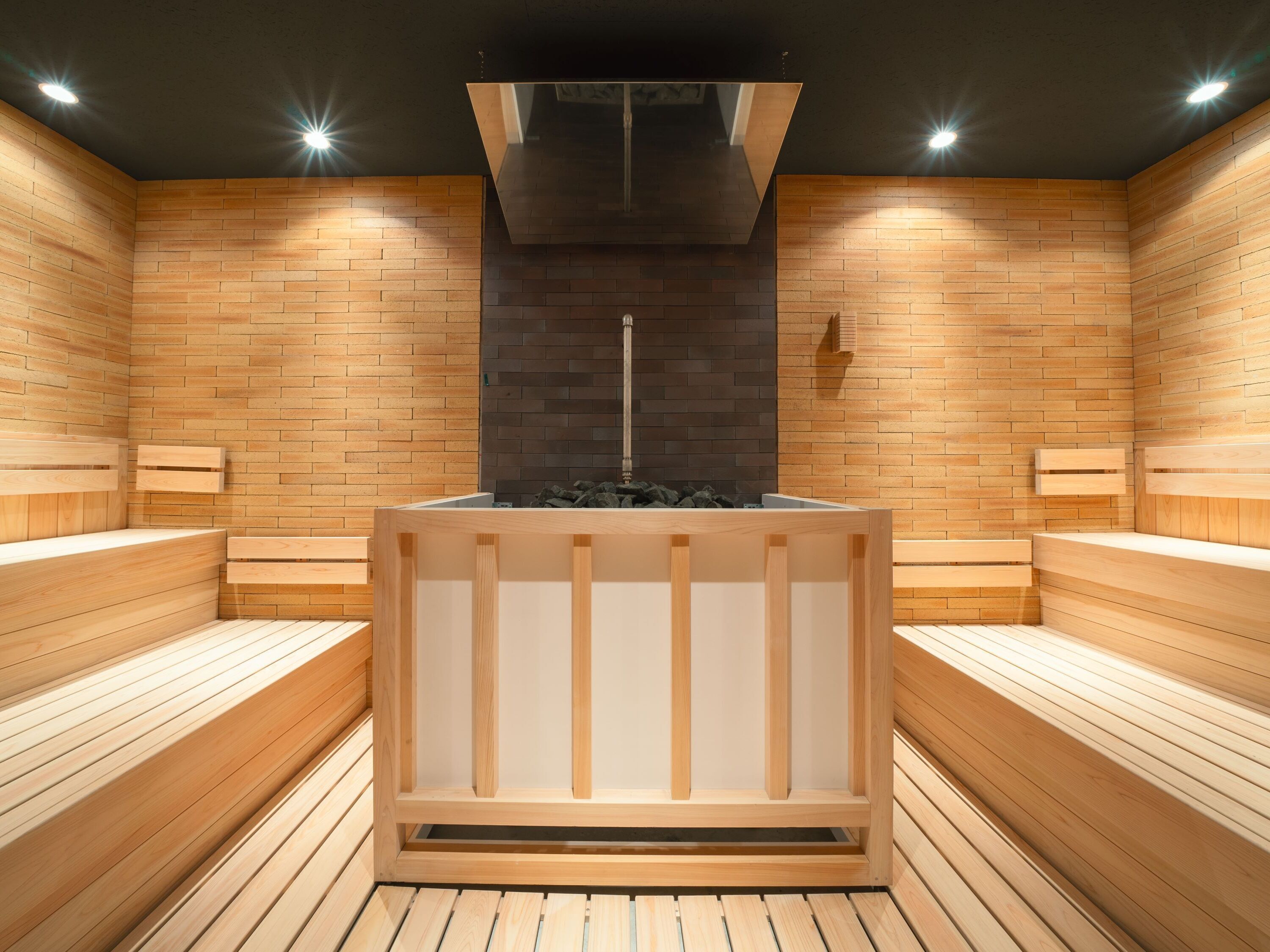 Un sauna avec des bancs en bois et un élément chauffant central.