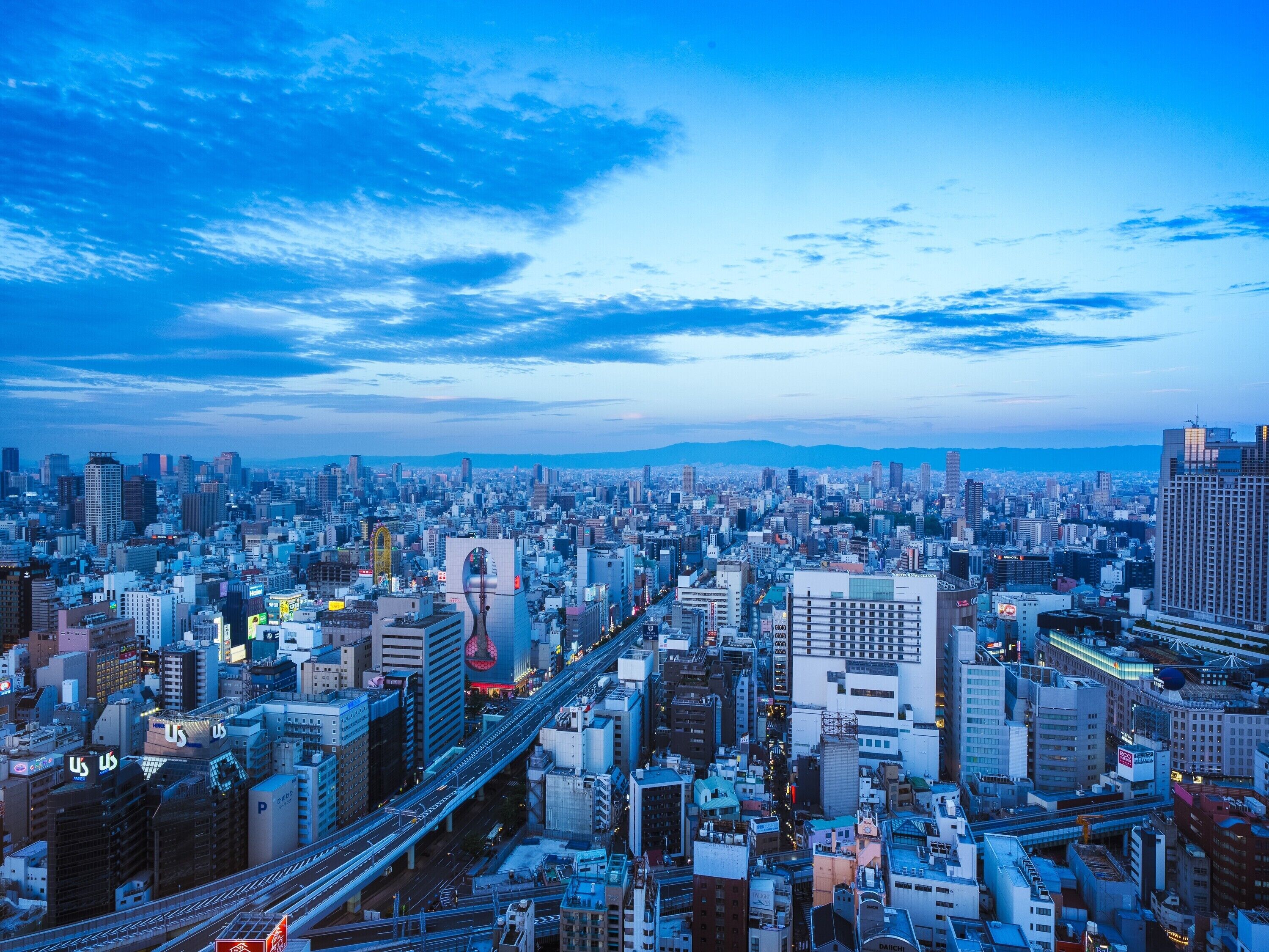 A cityscape with a dense urban environment, featuring a variety of building types and a prominent bridge structure.