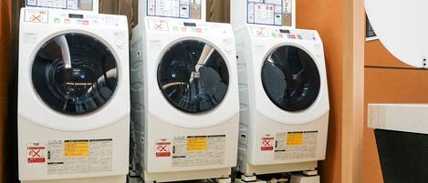 Three stacked front-loading washing machines in a room with wooden walls and a tiled floor.
