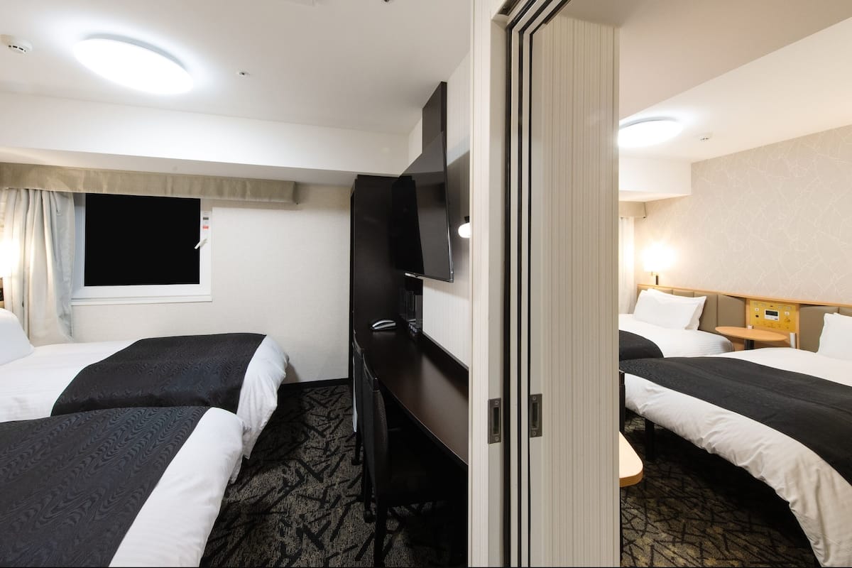 Een hotelkamer met twee bedden, een bureau, een televisie en een klein tafeltje.