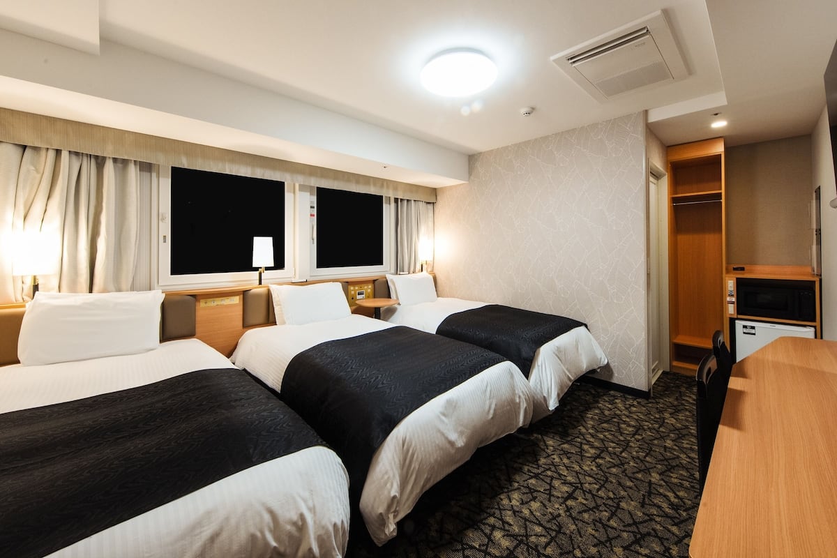 Een hotelkamer met twee bedden, een bureau, een magnetron en een kledingkast.