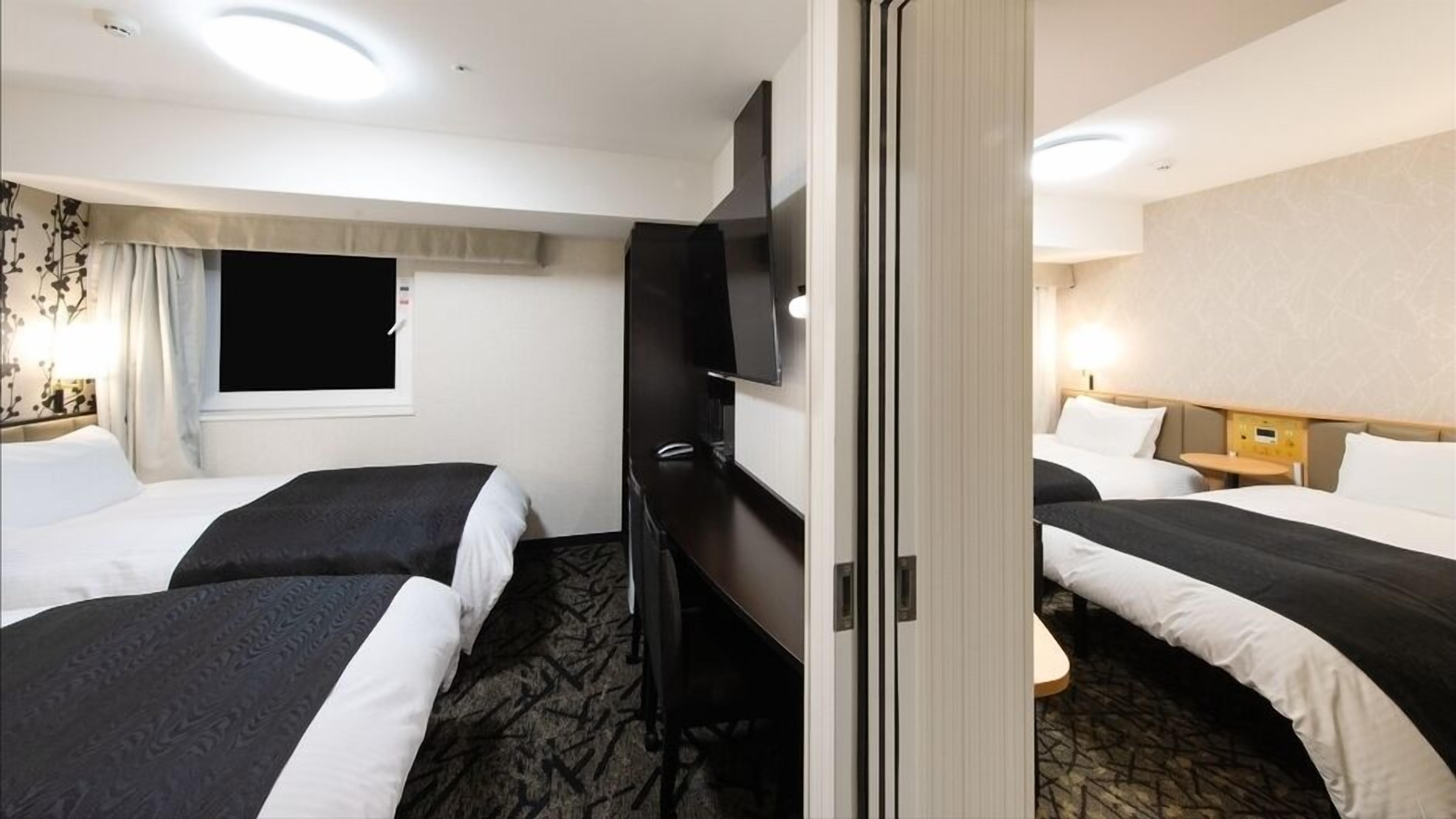 Une chambre d’hôtel avec deux lits, une télévision, une fenêtre avec des rideaux et une table de chevet avec une lampe.