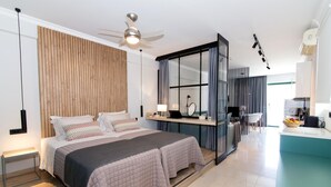 A modern hotel room with a large bed, a desk, a ceiling fan, and a view of the kitchen. - Phaedra's Studios in Kolymbari (Platanias)