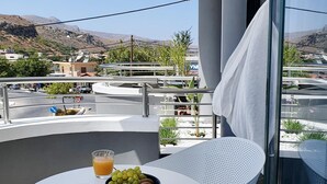 A balcony with a table, two glasses of orange juice, and a bowl of grapes. - Phaedra's Studios in Kolymbari (Platanias)