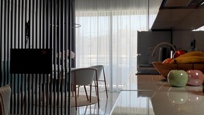 A modern kitchen with a large island, a dining area with chairs, and a kitchen counter with fruit. - Phaedra's Studios in Kolymbari (Platanias)