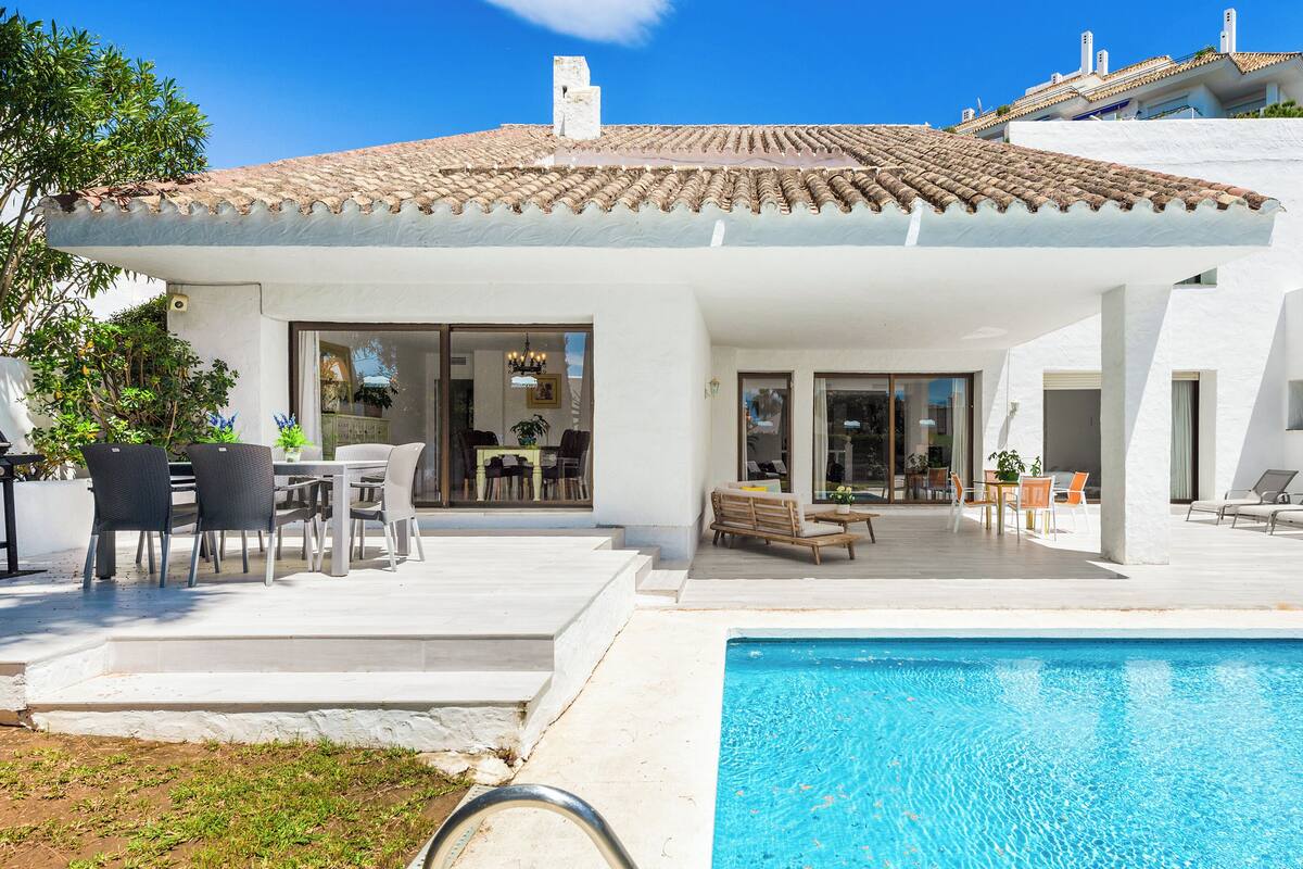 A modern villa with a swimming pool, outdoor seating, and a patio area.