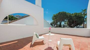 Relax on the outdoor terrace with a view of the surrounding buildings, surrounded by a potted plant and comfortable seating.