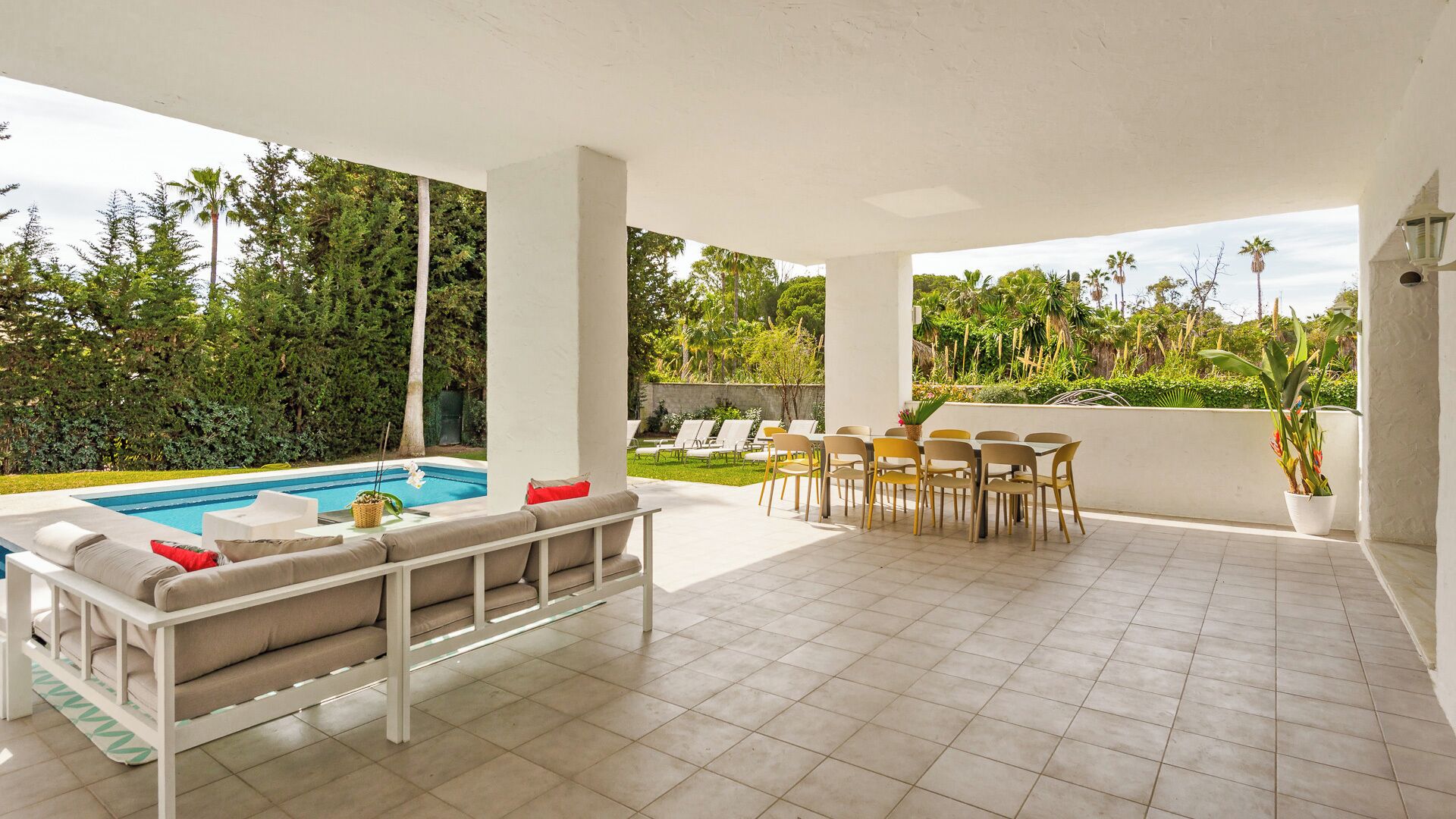 Un espacio al aire libre cubierto con piscina, asientos y una mesa de comedor.