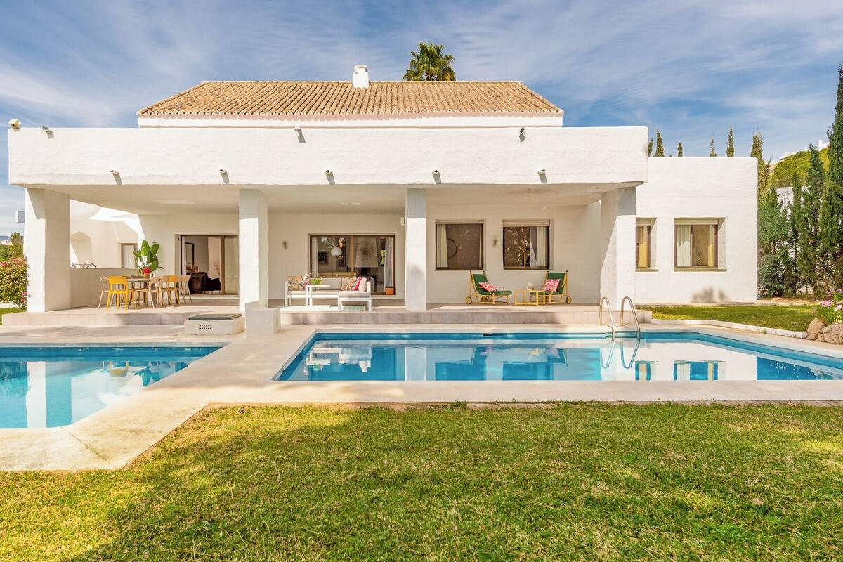 A modern two-story house with a swimming pool, outdoor seating, and a well-maintained garden.