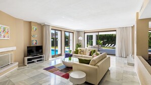 A modern living room with a flat-screen TV, a beige sofa, a coffee table, and a colorful rug.